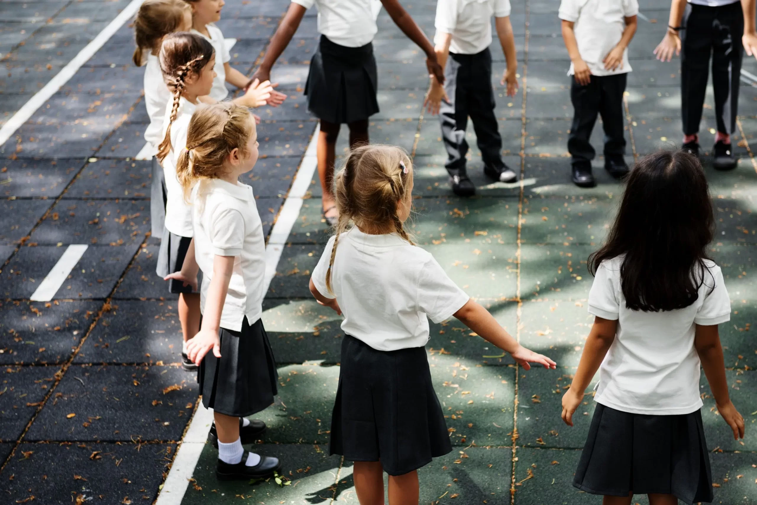 A group of Primary School students playing together outside in a circle on a playground.